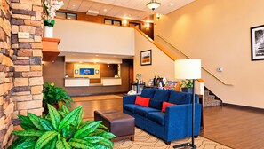 A hotel lobby with a reception desk, a staircase, a blue sofa, and a large potted plant. - Manitou Pikes Peak Hotel (Manitou Springs)