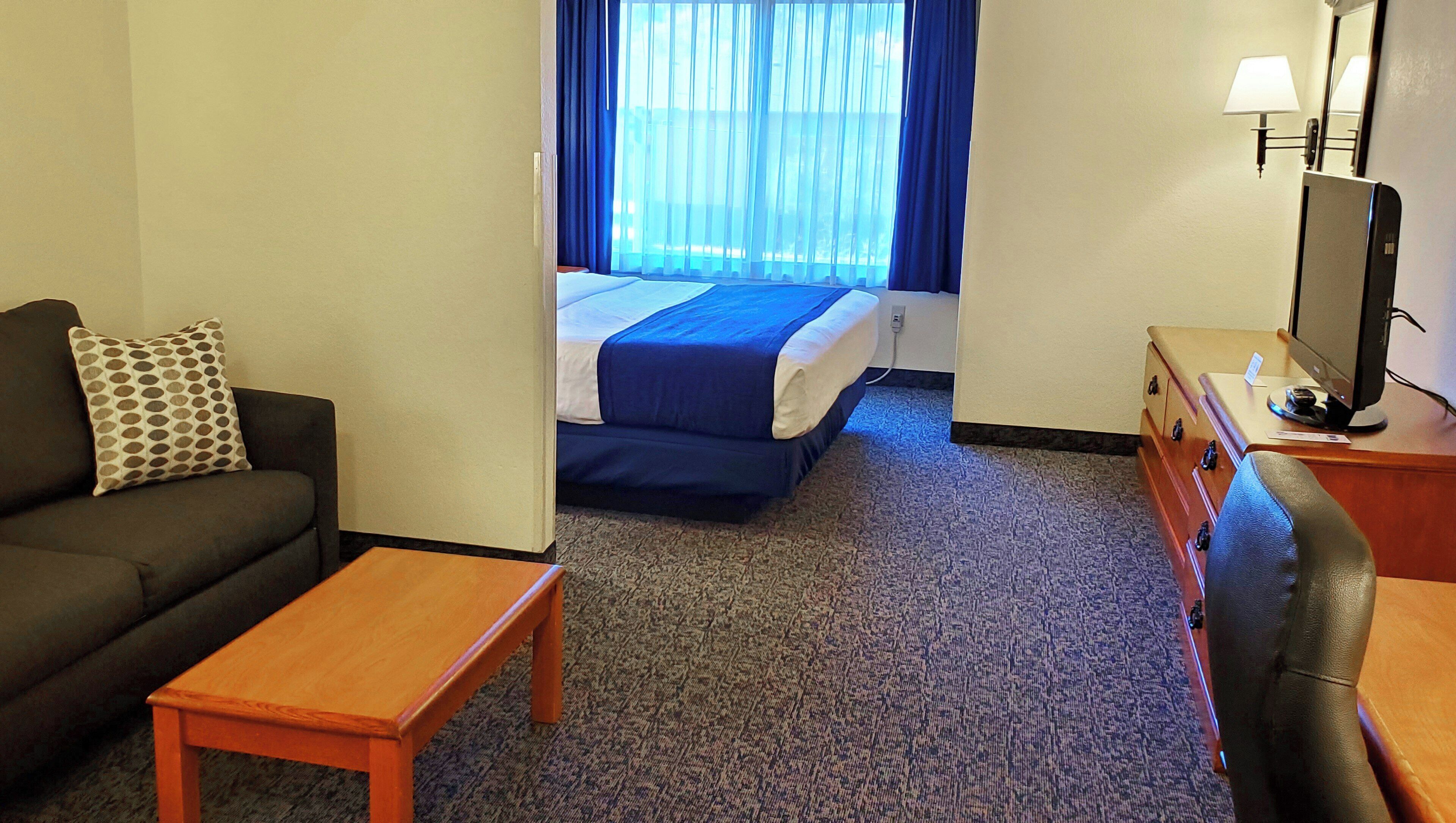 A hotel room with a bed, a sofa, a desk, and a chair.