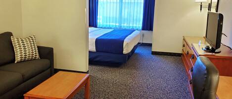 A hotel room with a bed, a sofa, a desk, and a chair.