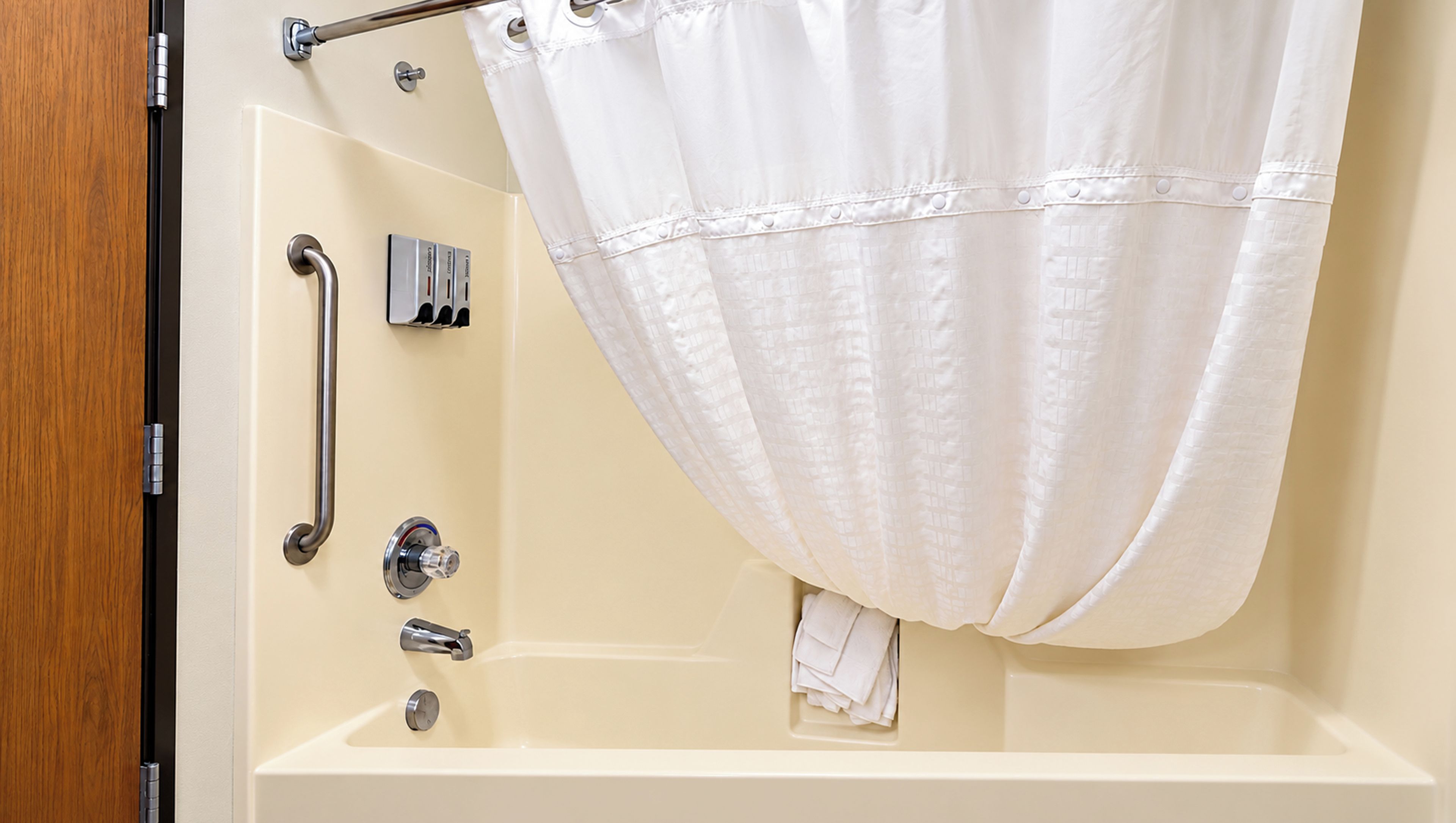 Une salle de bain équipée d’une baignoire, d’une douche et d’une barre d’appui.