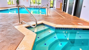 An indoor swimming pool with a tiled edge, a metal ladder, and a tiled floor. - Manitou Pikes Peak Hotel (Manitou Springs)