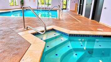 Una piscina interior con borde de azulejos, una escalera metálica y suelo de baldosas.