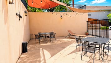 An outdoor patio with a table and chairs, string lights, and a sunshade.