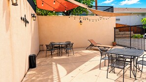 An outdoor patio with a table and chairs, string lights, and a sunshade. - Manitou Pikes Peak Hotel (Manitou Springs)