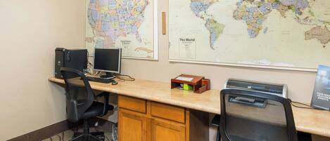 A workspace with two monitors, a keyboard, a mouse, a printer, and a desk with chairs.