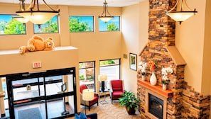 A lobby with a fireplace, seating area, and a teddy bear on a shelf. - Manitou Pikes Peak Hotel (Manitou Springs)
