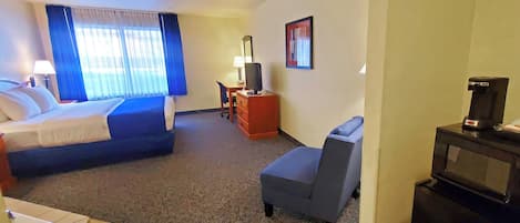 A hotel room with a bed, a desk, a chair, a television, and a coffee machine.