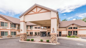 A hotel with a covered entrance, multiple windows, and a stone pillar. - Manitou Pikes Peak Hotel (Manitou Springs)