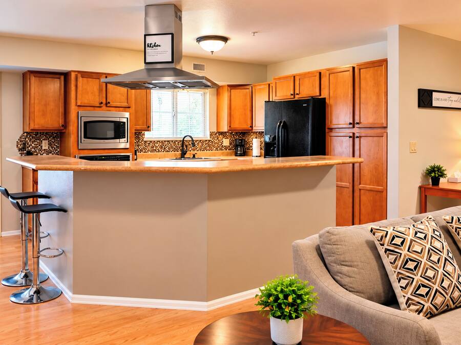 Una cocina moderna con armarios de madera, electrodomésticos de acero inoxidable y una isla central.