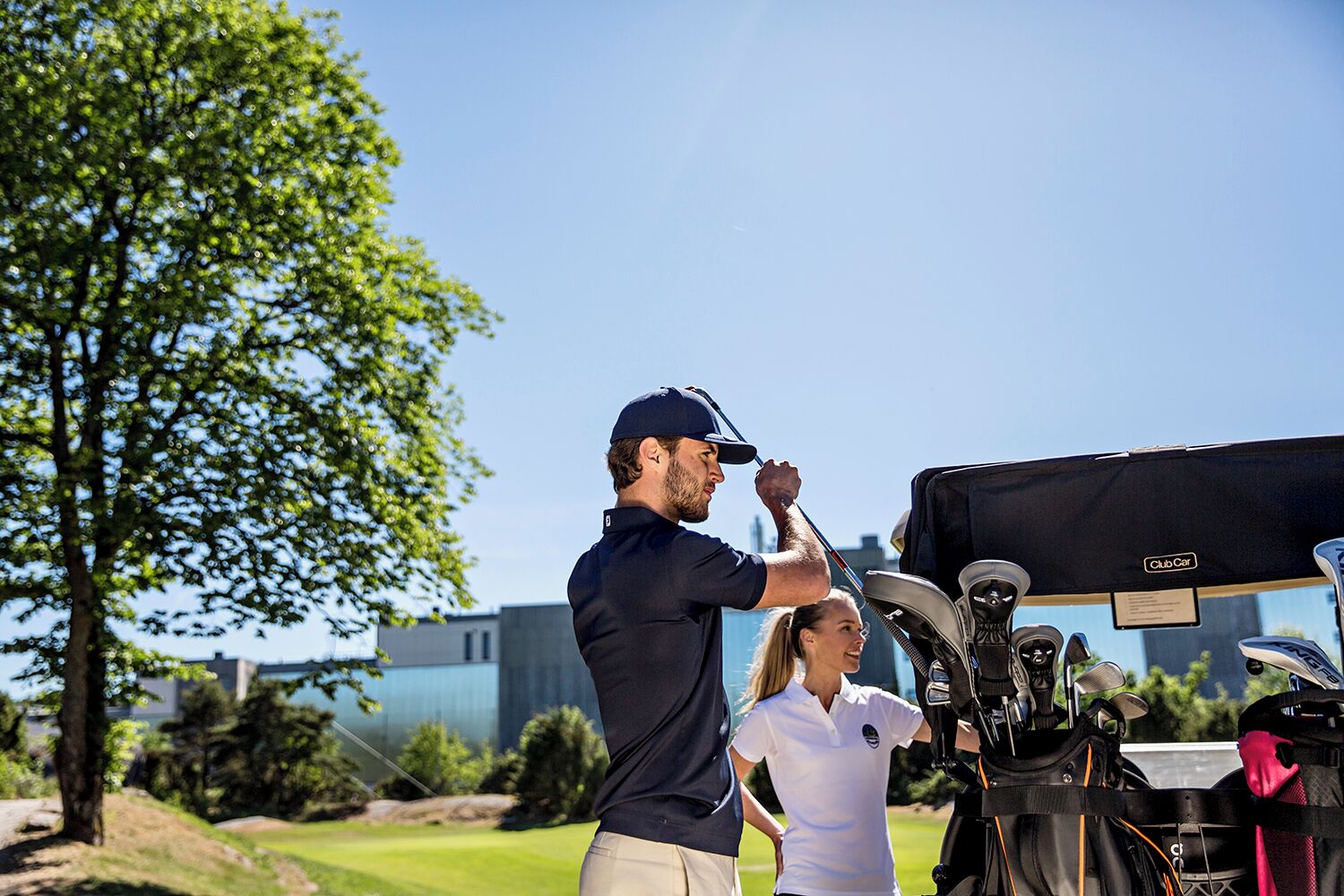 A golf course with a tent labeled 'Club Car' and golf equipment.