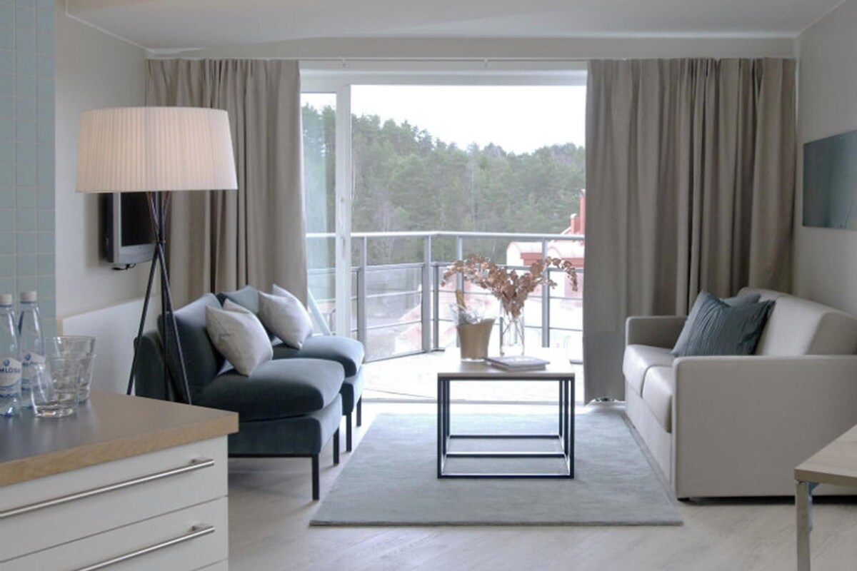 Uma sala de estar moderna com um sofá, uma mesa de centro e uma área de jantar com mesa e cadeiras.