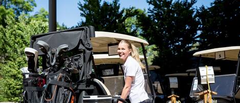 Un carrito de golf con una persona a su lado, un bolso de golf y un cartel con el número 5.