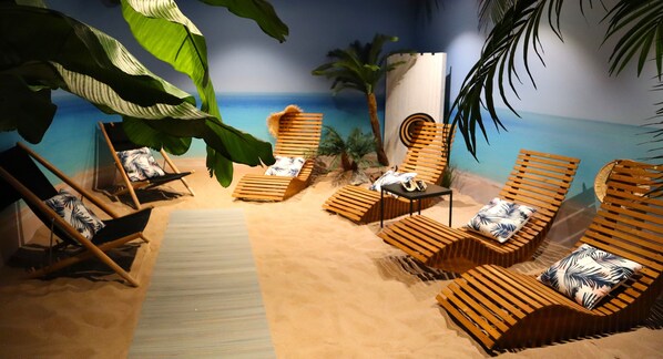 Una habitación con temática playera, que incluye sillones de madera, una mesita y vista al océano.