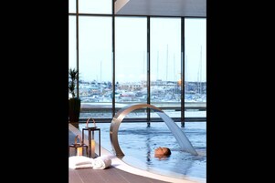 Una piscina interior moderna con vistas a un paisaje nevado y edificios.