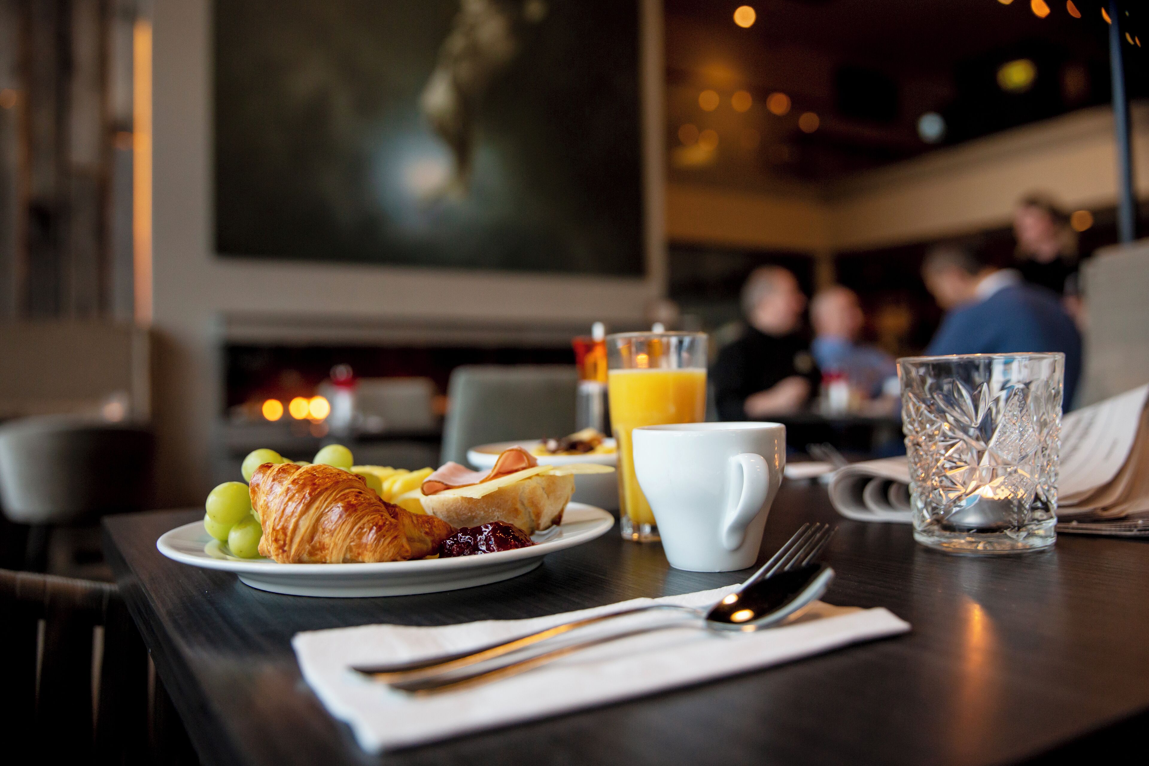 A breakfast setting with croissants, grapes, and orange juice on a table.
