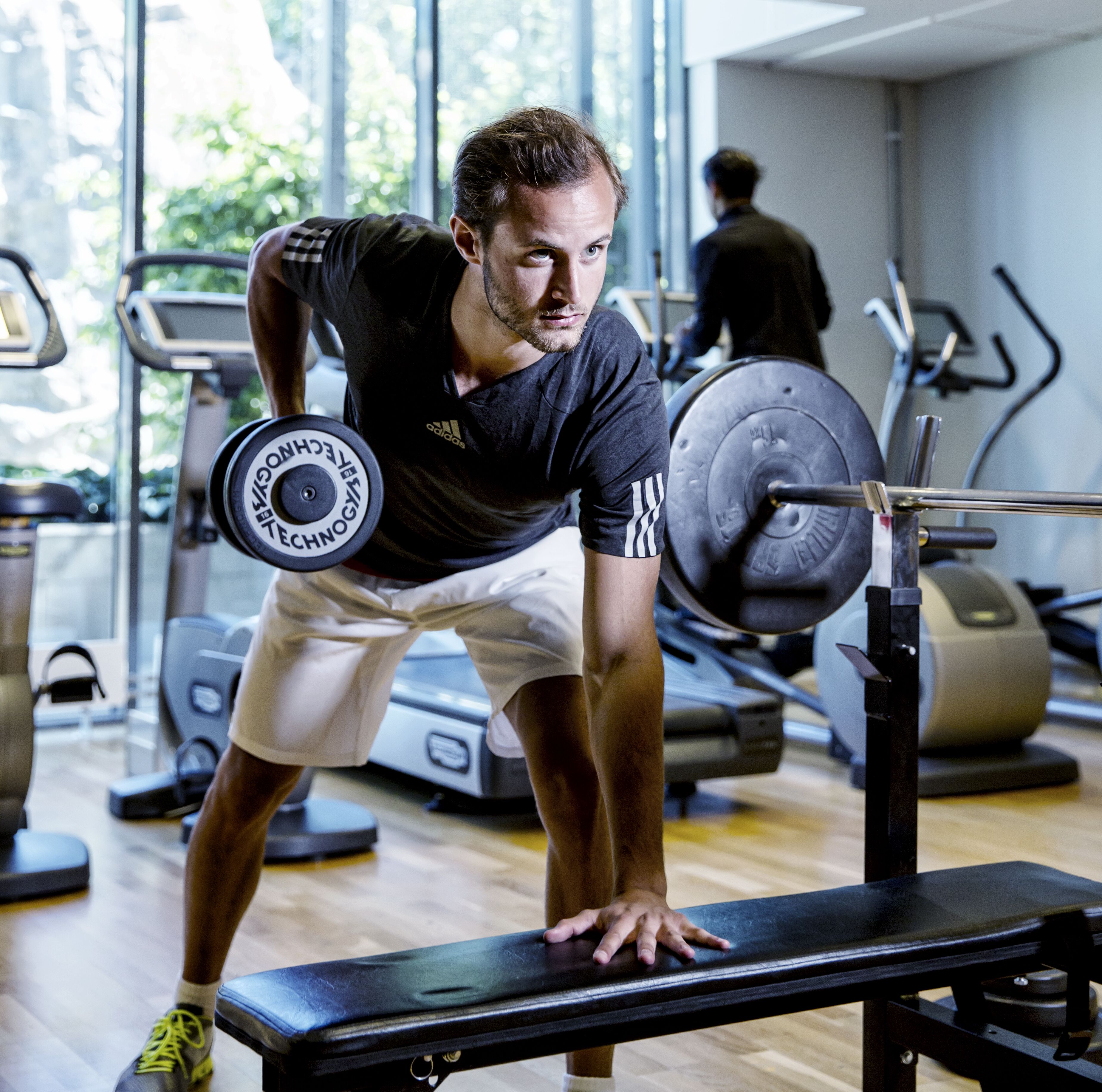 Un gimnasio con equipo de ejercicio, incluyendo una banca y una barra.