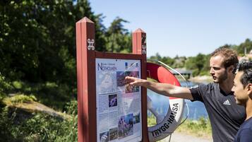 Un panneau d’information rouge, avec du texte et des images, fixé sur un poteau.