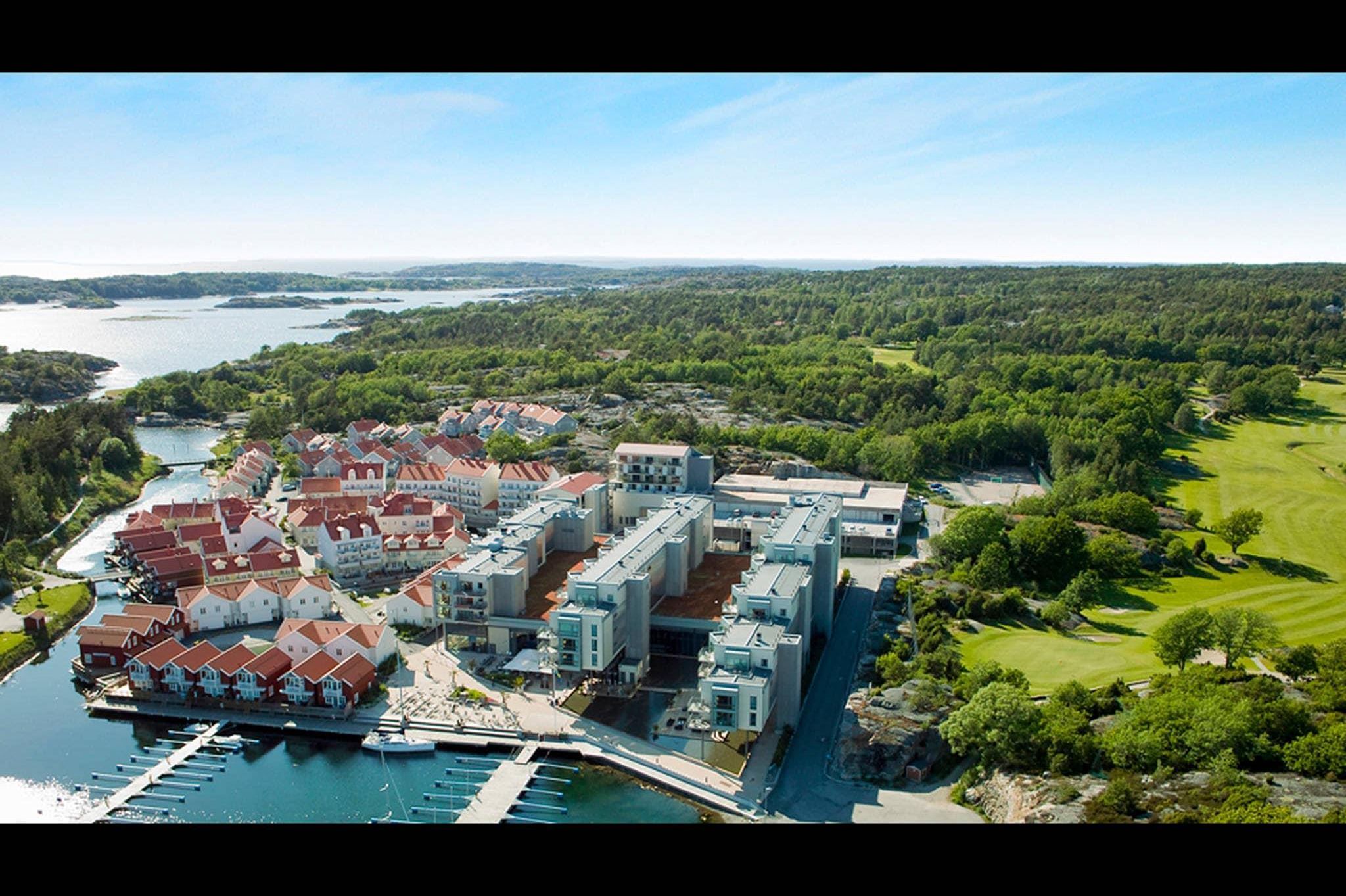 An aerial view of a coastal resort with multiple buildings, a marina, and surrounding greenery.