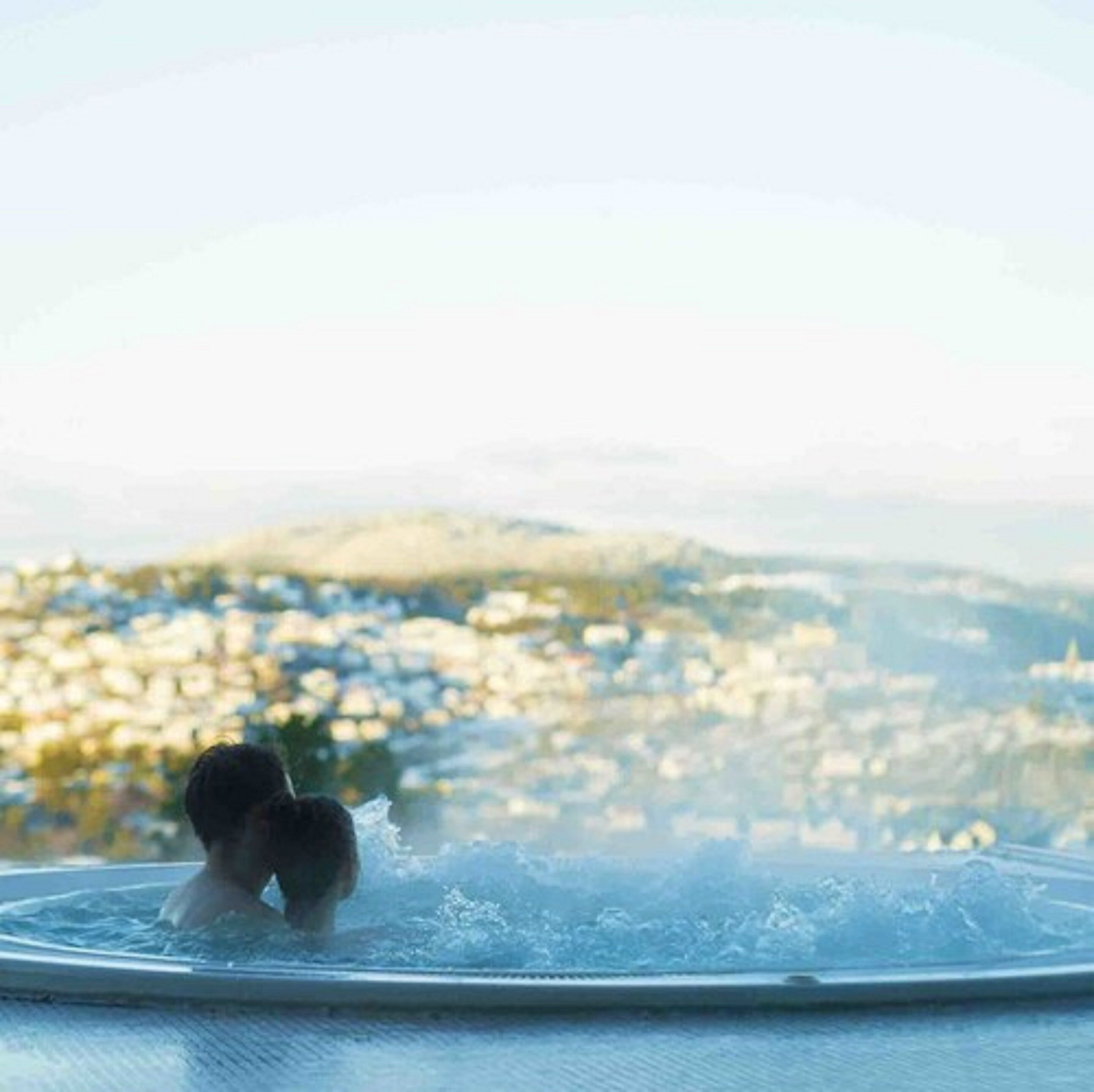 A person in a hot tub with a cityscape view in the background.