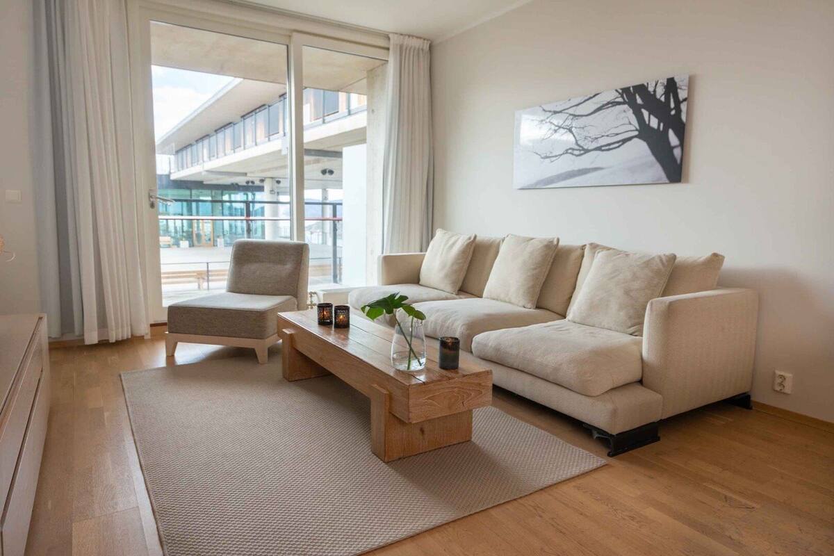 A modern living room with a sofa, a chair, a wooden coffee table, and a plant.