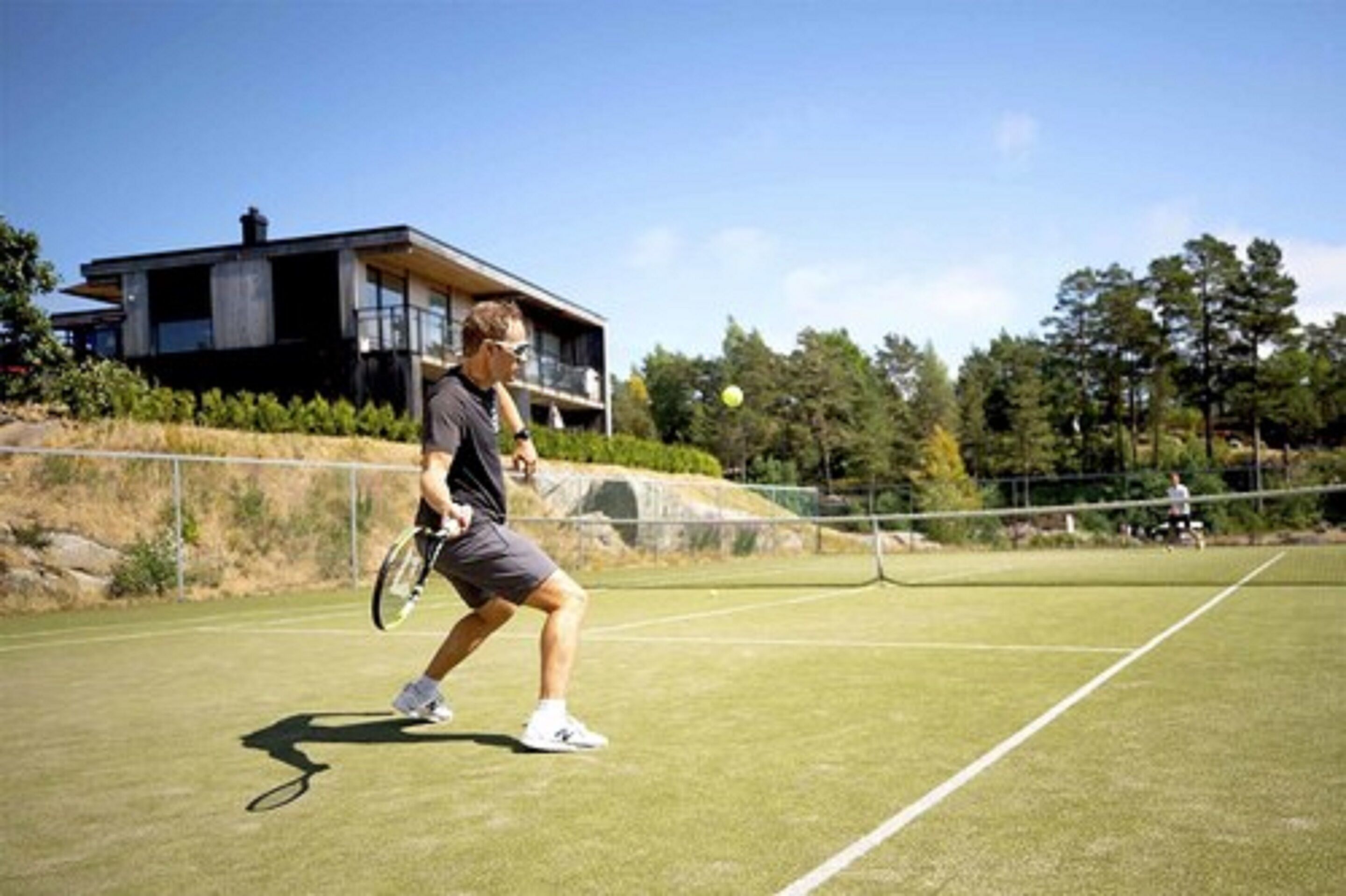 Una cancha de tenis con un edificio moderno al fondo.