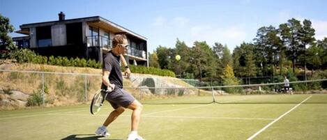 Una cancha de tenis con un edificio moderno al fondo.