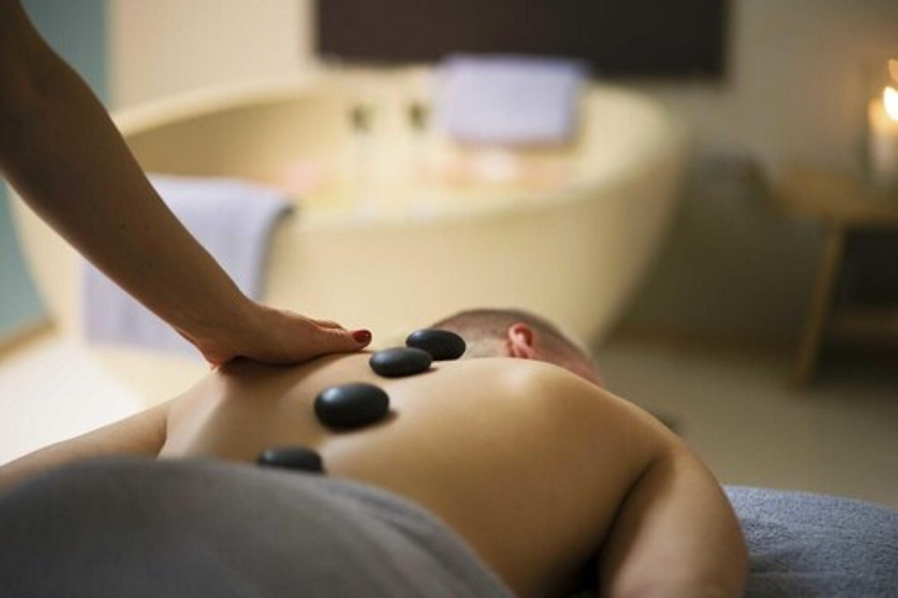 A person receiving a back massage with heated stones.