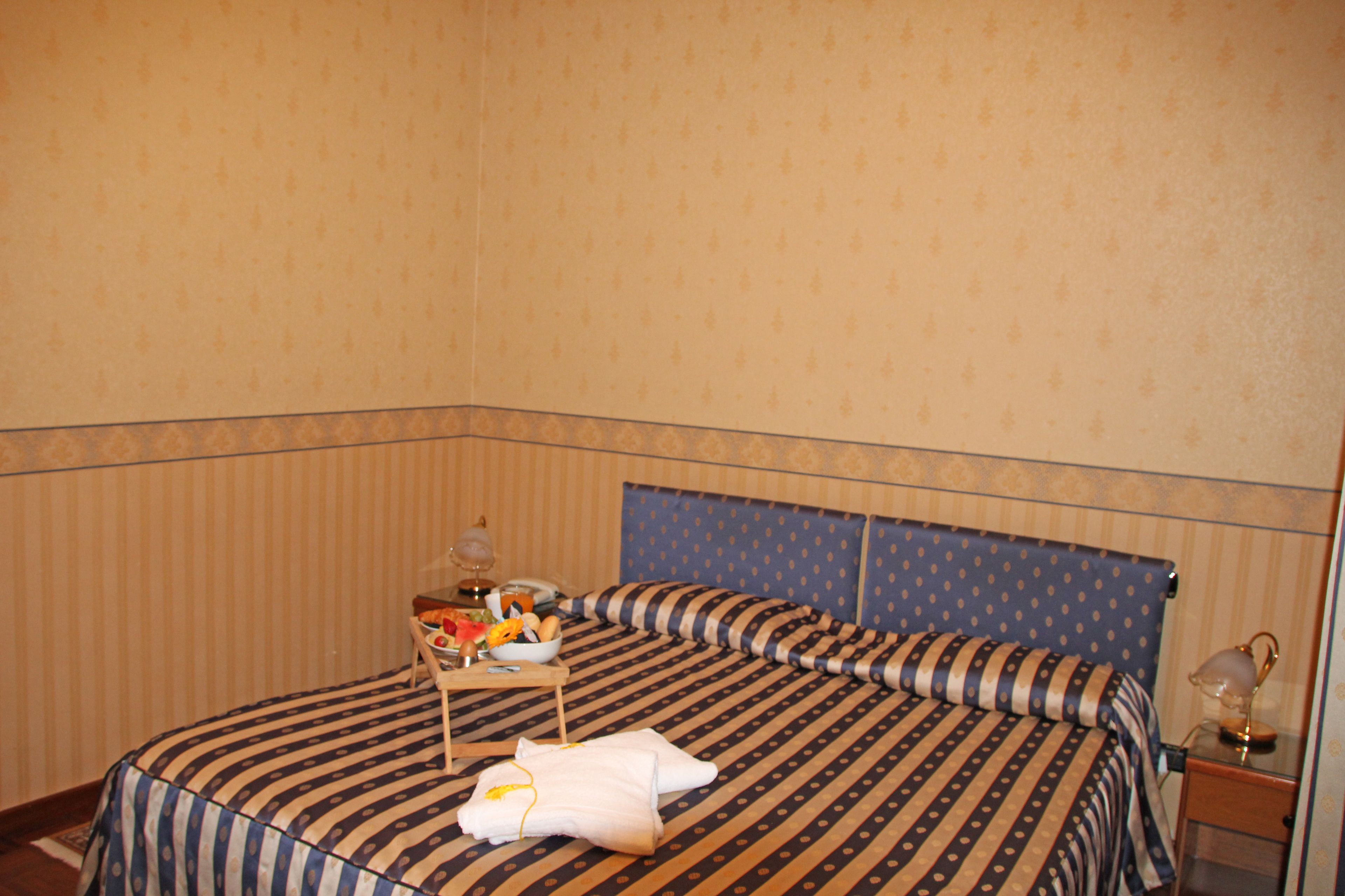 A hotel room with a bed, a bedside table, and a nightstand.