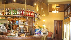 Una zona de bar con diversas botellas de licores, una máquina de café y un mostrador con alimentos.
