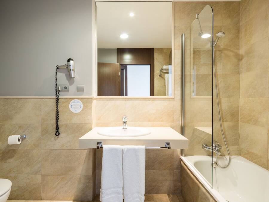 A modern bathroom with a sink, toilet, and bathtub.