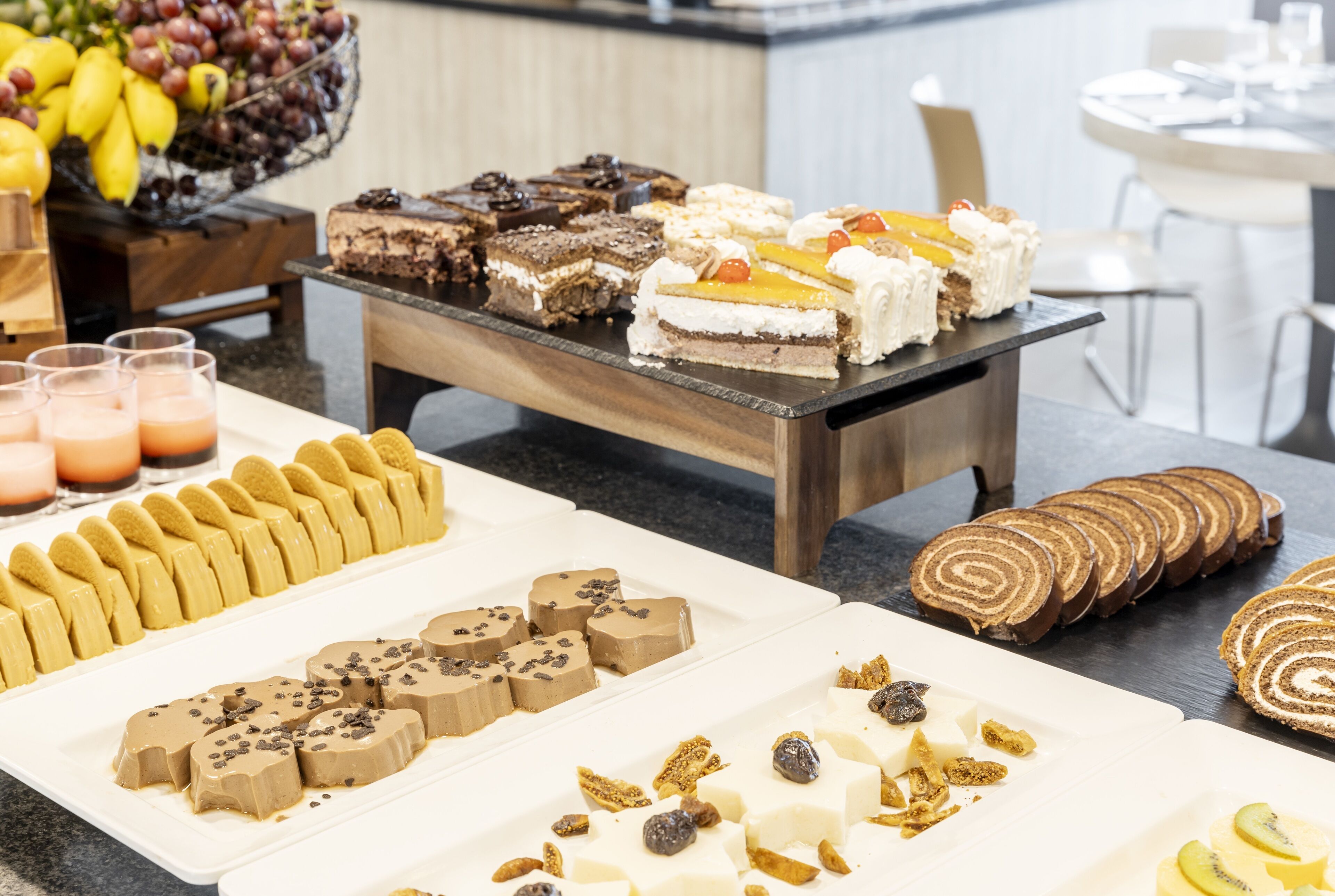 Monipuolinen buffet, jossa on tarjolla erilaisia jälkiruokia ja hedelmiä.
