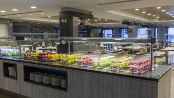 Un área de bufé con diversos alimentos y un espacio de estar con mesas y sillas.