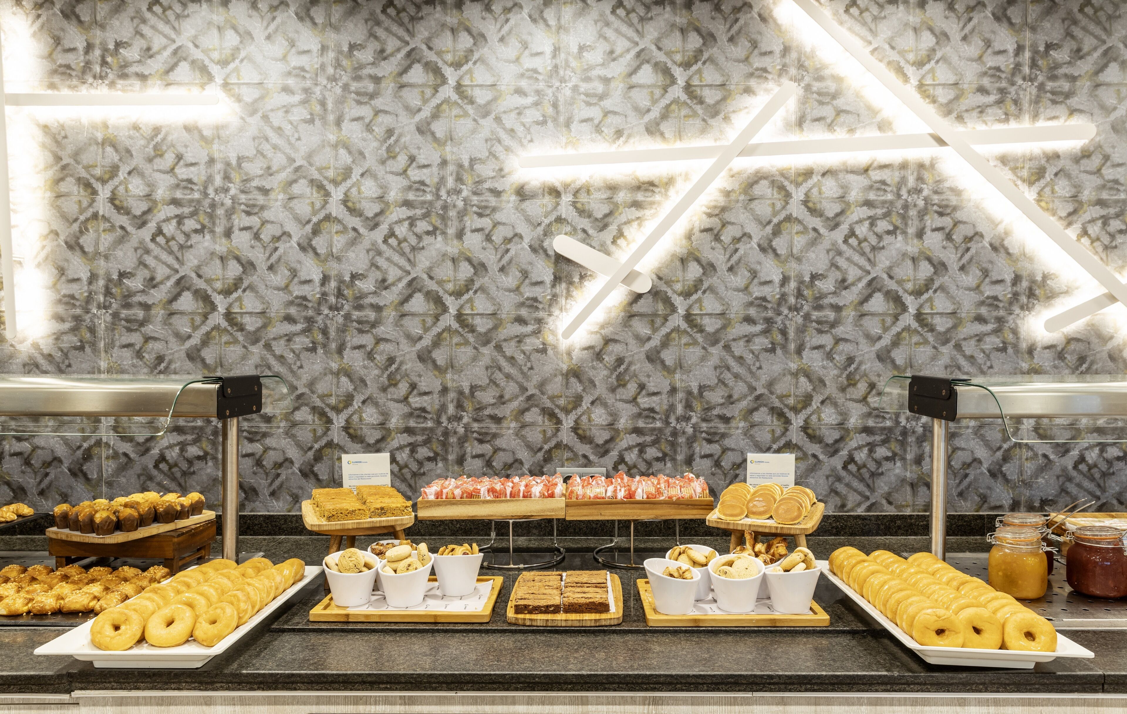 A buffet with various food items and a patterned wall with illuminated lines.