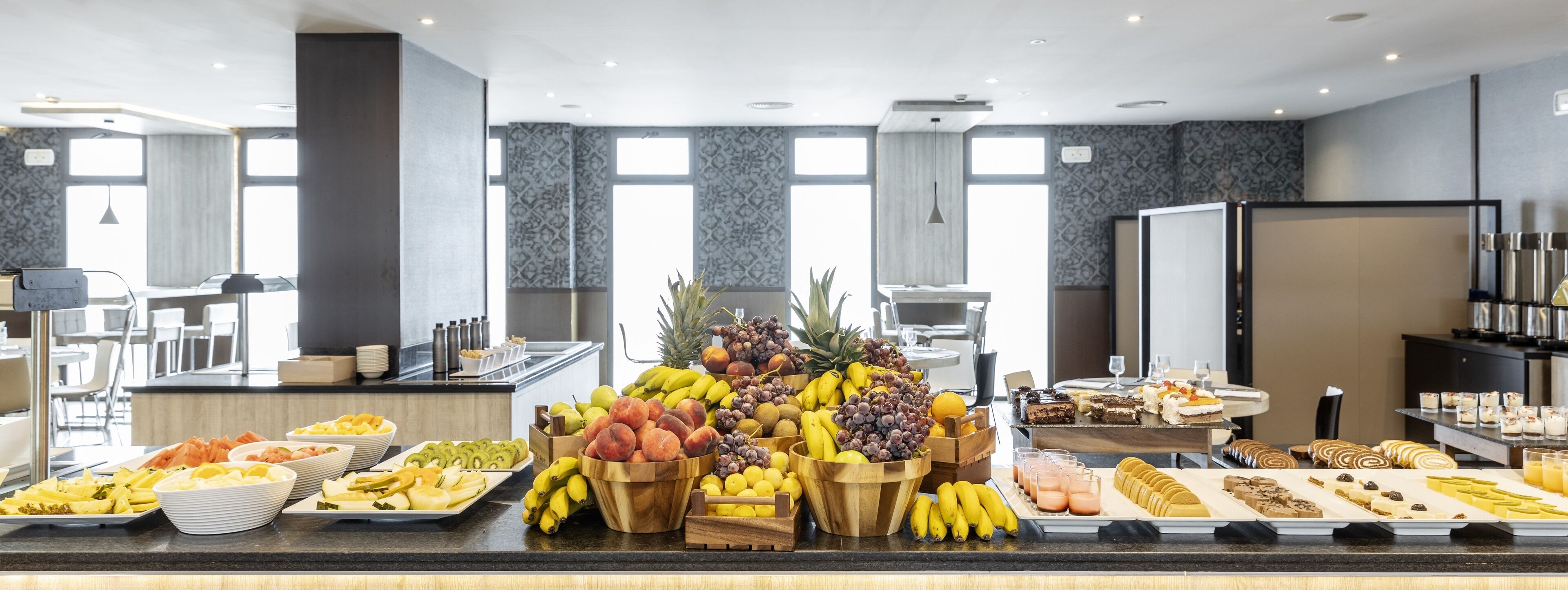A buffet with various fruits, pastries, and beverages.