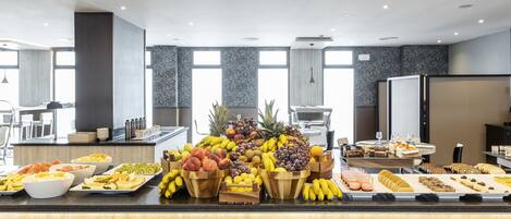 A buffet with various fruits, pastries, and beverages.