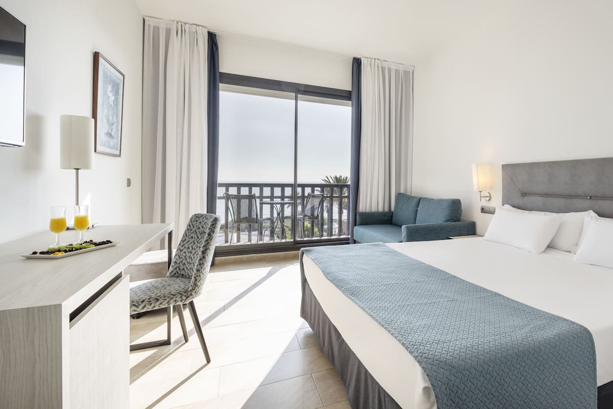 Habitación doble, vista al mar | Edredón, minibar, caja de seguridad en la habitación y escritorio