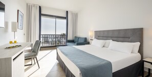 Habitación doble, vista al mar | Edredón, minibar, caja de seguridad en la habitación y escritorio 