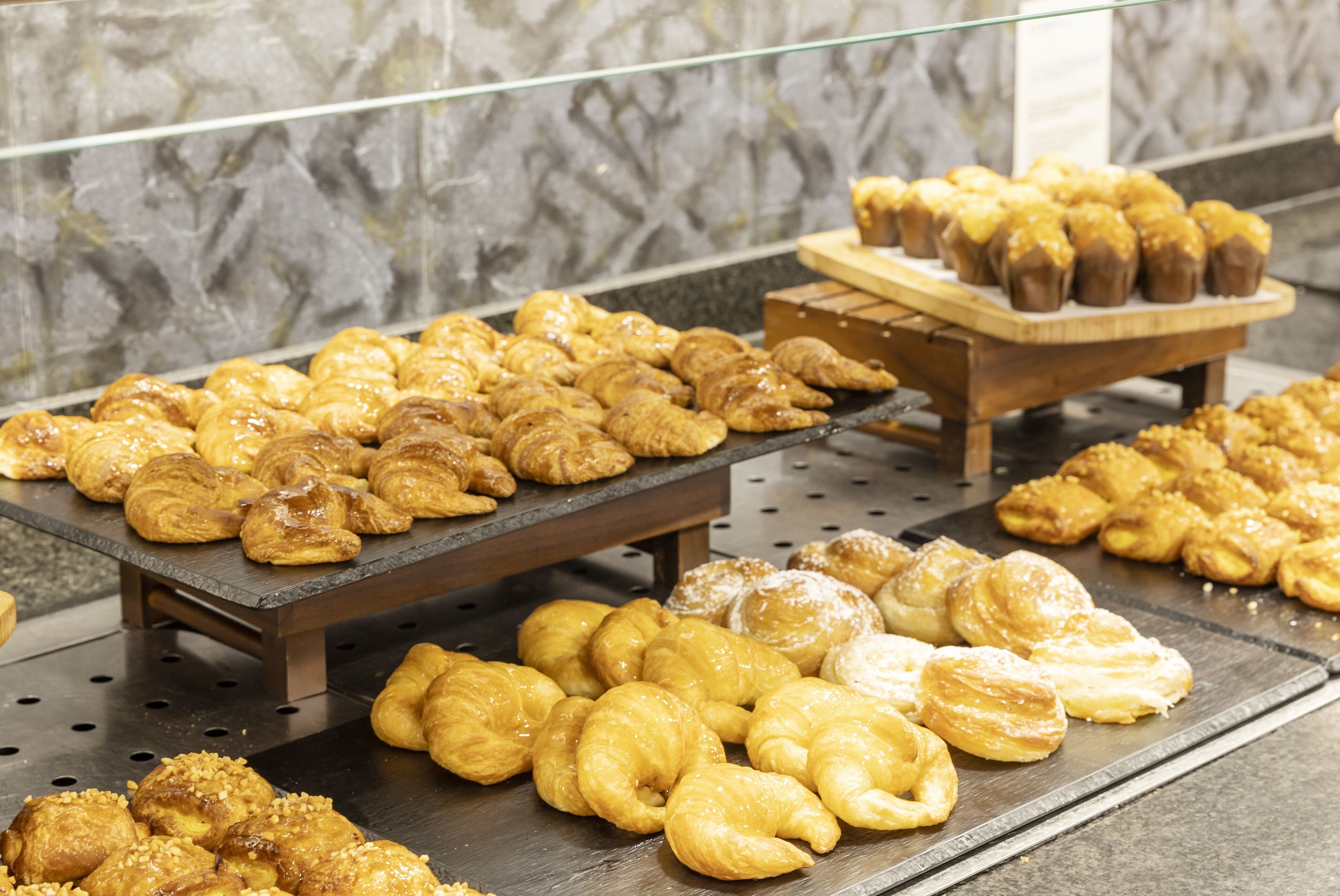 Una exhibición de pasteles variados en bandejas, en un ambiente de panadería.
