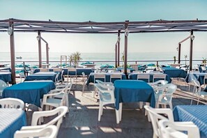 A beachside restaurant with outdoor seating, tables, and umbrellas. - La Piramide (Roccalumera)