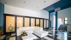 Un vestíbul modern amb un sofà seccional blanc, una taula de centre de vidre i un paviment a escacs.