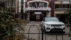 Un hotel con fachada clásica, varios balcones y un coche estacionado al frente.