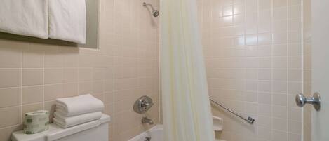 A bathroom with a bathtub, toilet, and shower curtain.