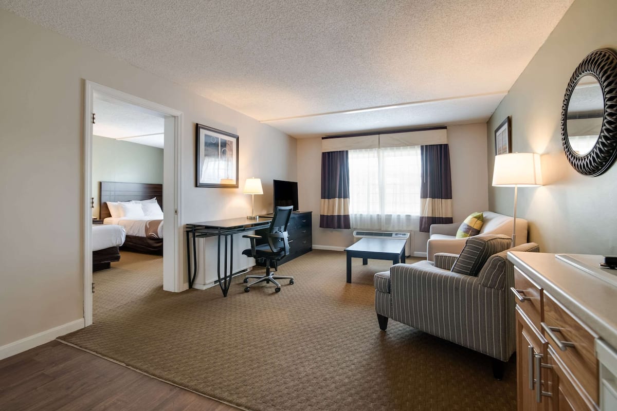 Quarto de hotel com cama, escrivaninha com cadeira, sofá, mesinha e cómoda.