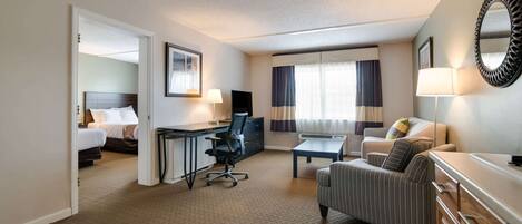 Ein Hotelzimmer mit einem Bett, einem Schreibtisch mit Stuhl, einer Couch, einem kleinen Tisch und einer Kommode.