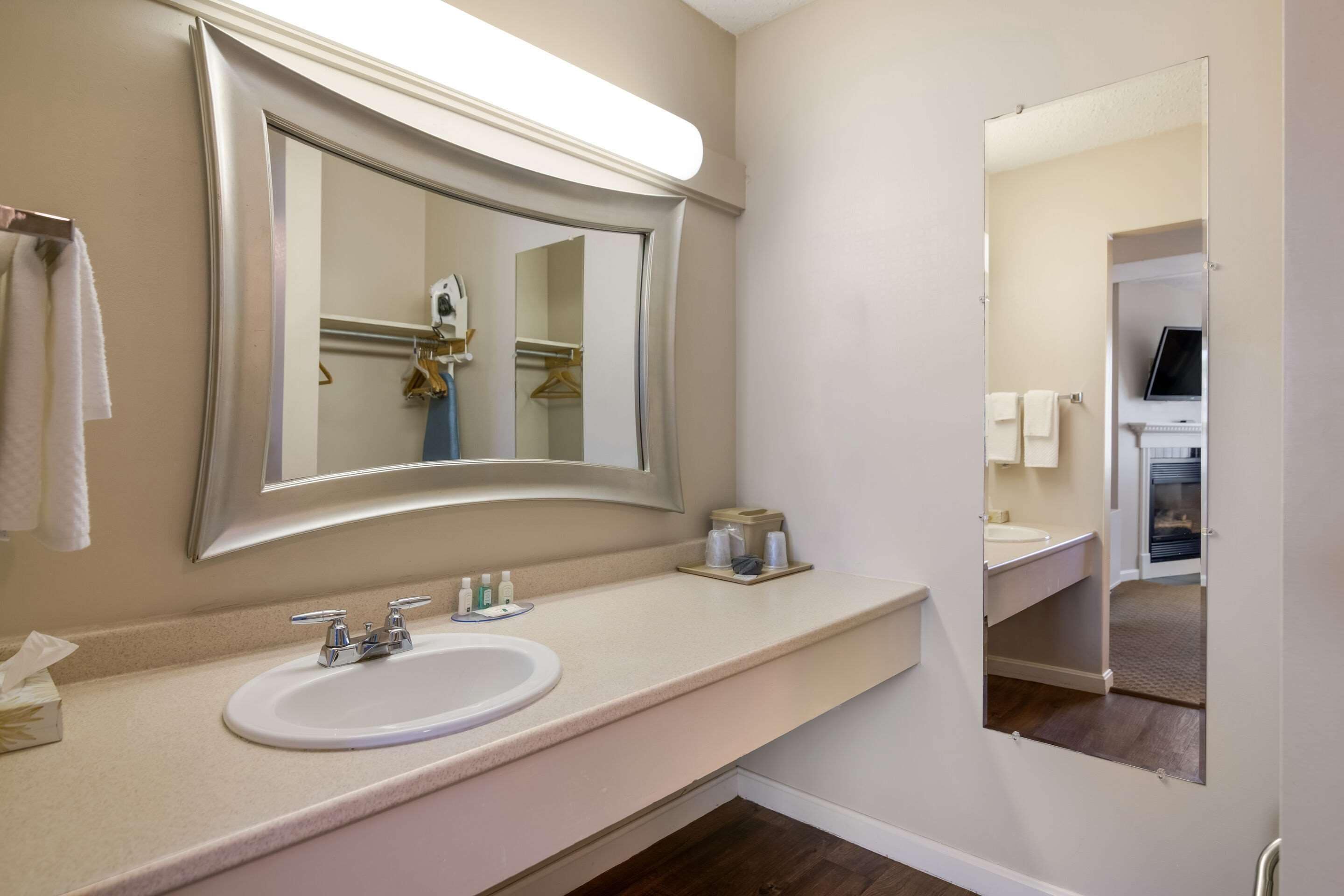 A bathroom with a large mirror, a sink, and a towel rack.