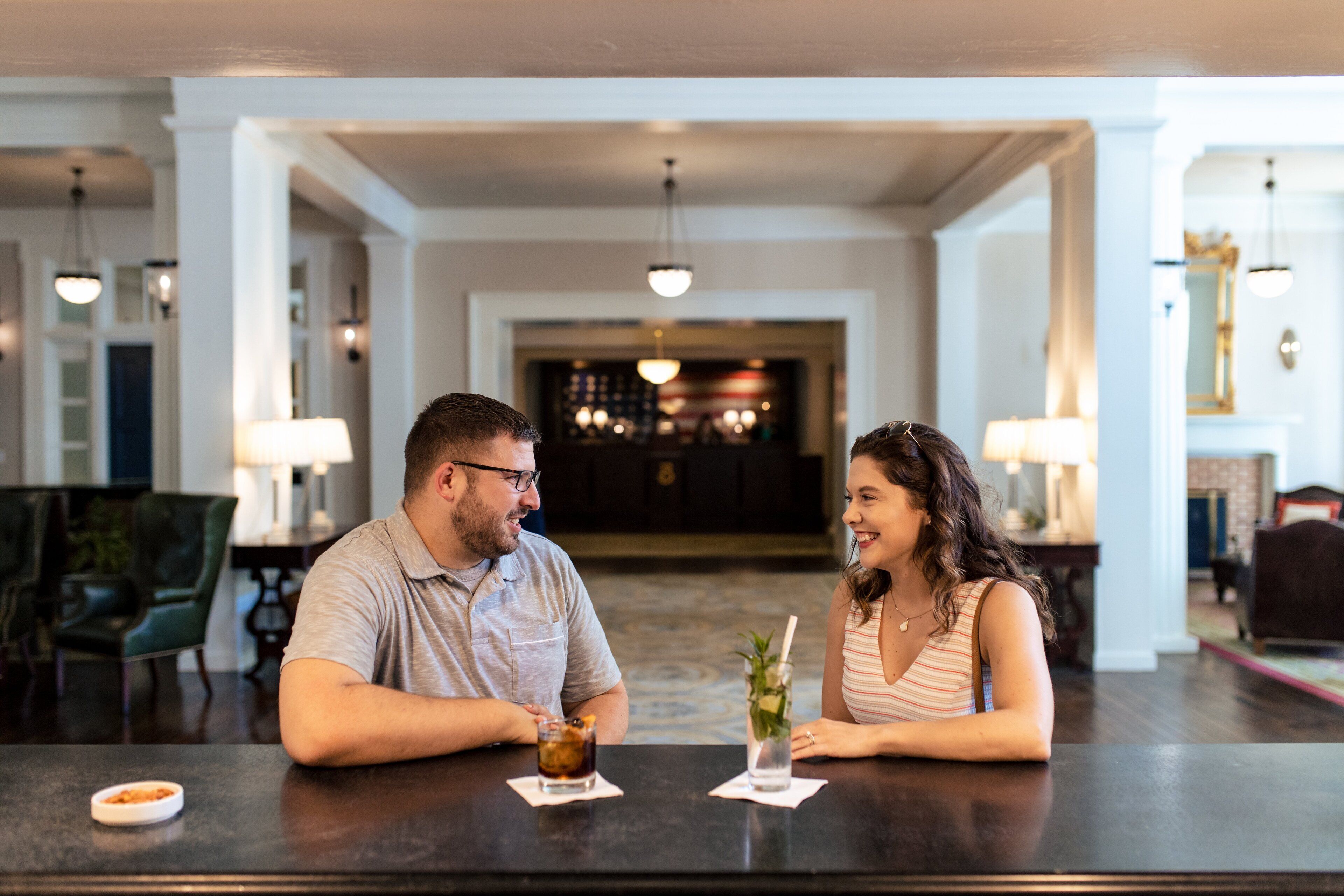 Una pareja sentada en la barra del vestíbulo de un hotel, con vista al interior.