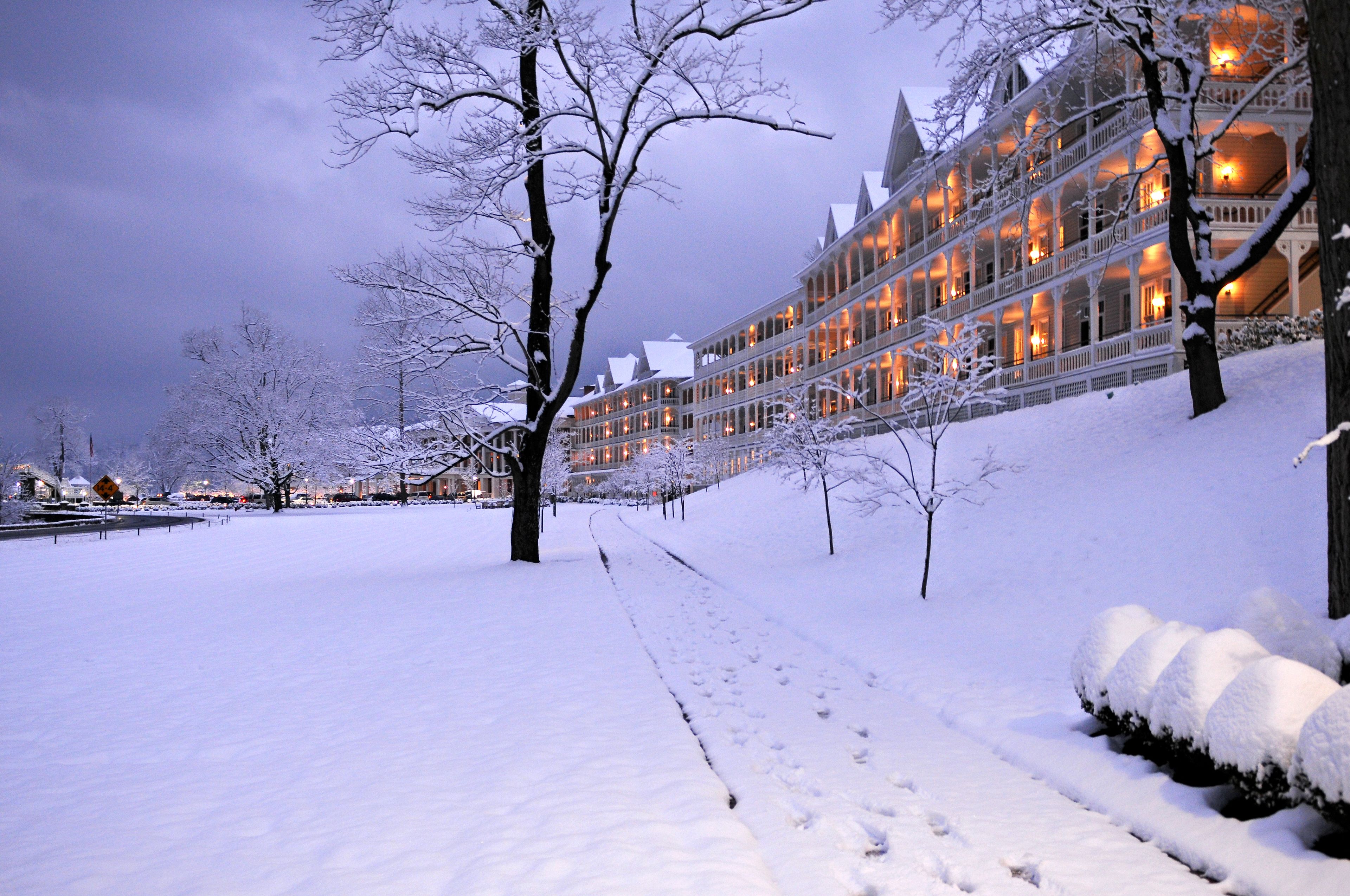 A snow-covered hotel with multiple balconies and a snow-covered pathway.
