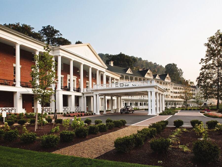 A hotel with a covered walkway, brick facade, and landscaped gardens.