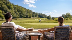 Deux personnes sont assises à une table, devant laquelle s’étend un terrain de golf.