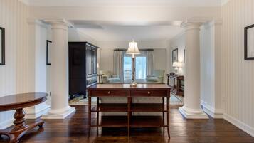 A spacious room with a wooden table and chairs, a lamp, and a view of a living area with a fireplace.